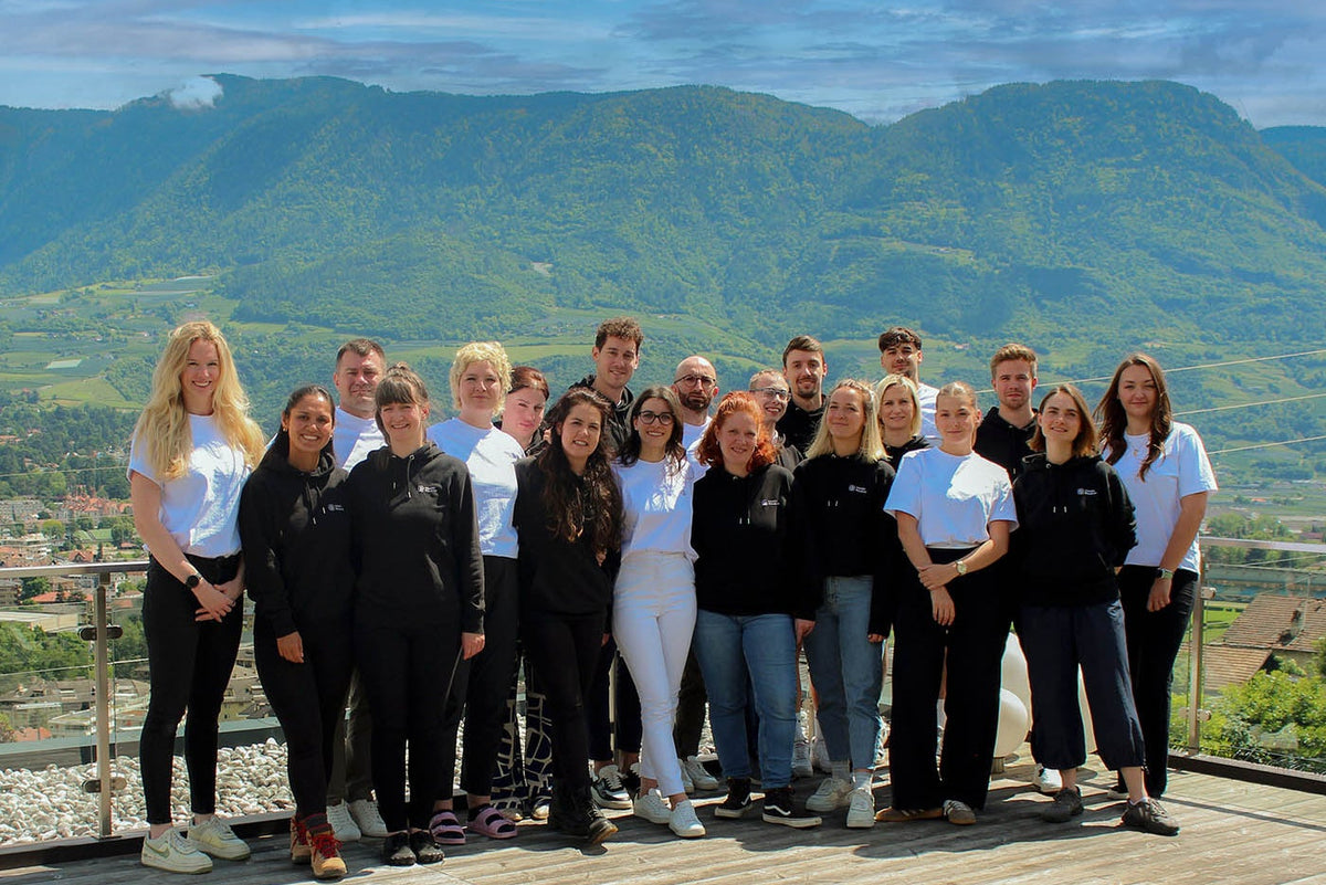 Das gesamte Health Routine Team auf einer Terrasse mit Blick über das Tiroler Bergpanorama